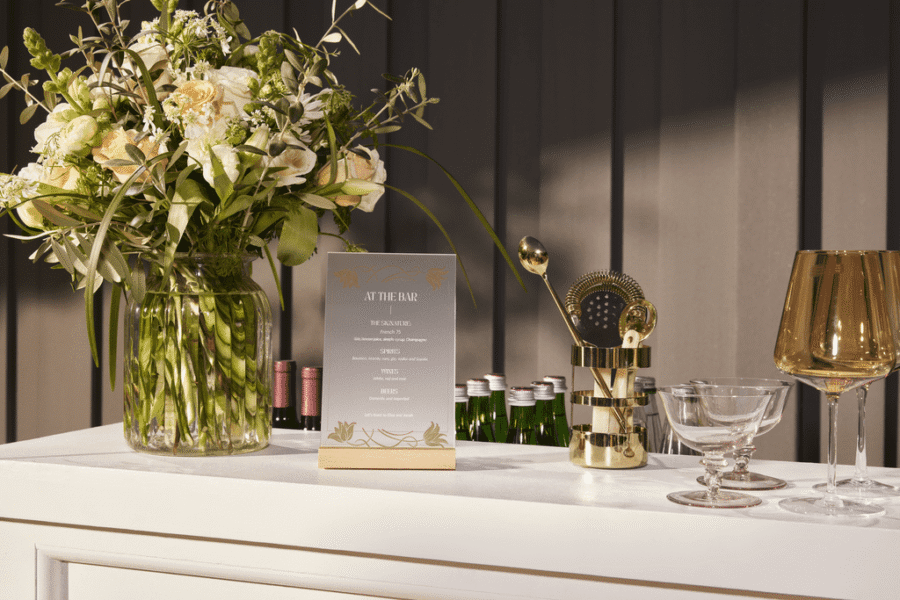 A wedding bar with flowers, a menu and glasses