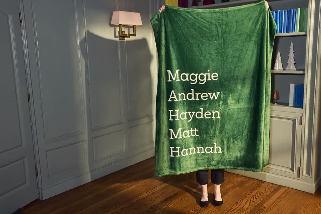 Woman holding custom fleece blanket with a list of her children’s names.
